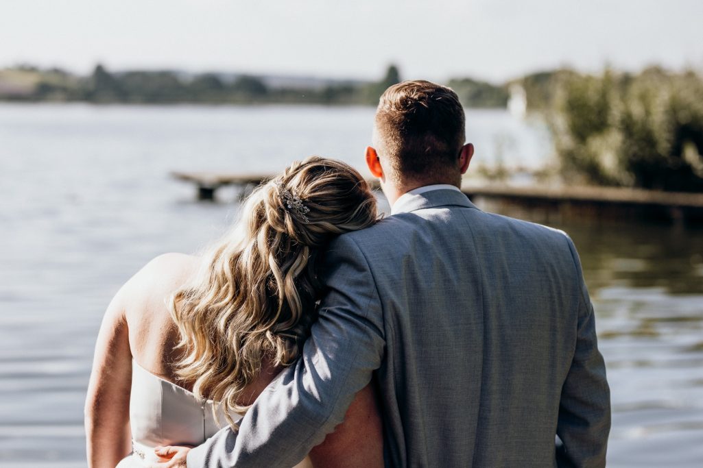 Hochzeitspaar Nina Hübner Göttingen Hochzeitsplanung Braut und Bräutigam stehen an einem Gewässer, umarmt, mit Blick auf den Horizont.